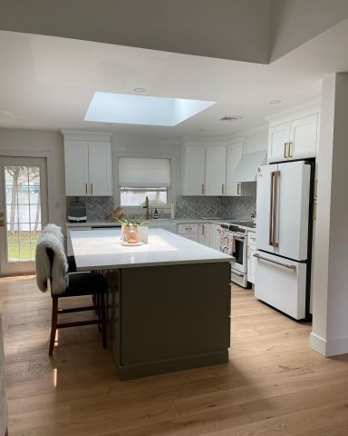 Modern kitchen with white cabinets, large island, and skylight providing natural light.