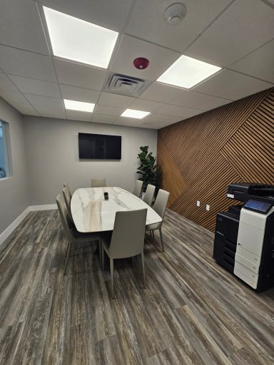 A modern conference room with a large table, chairs, and a printer in the corner.