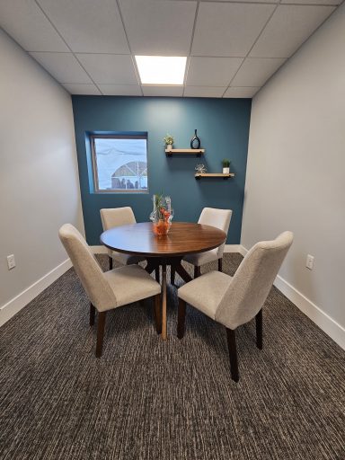 A small meeting room featuring a round table and four upholstered chairs.