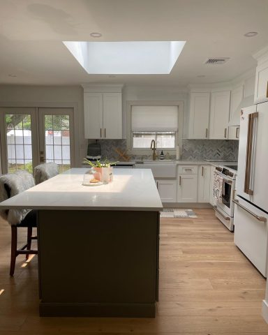 Bright kitchen with white cabinets, a large island, and a skylight overhead.