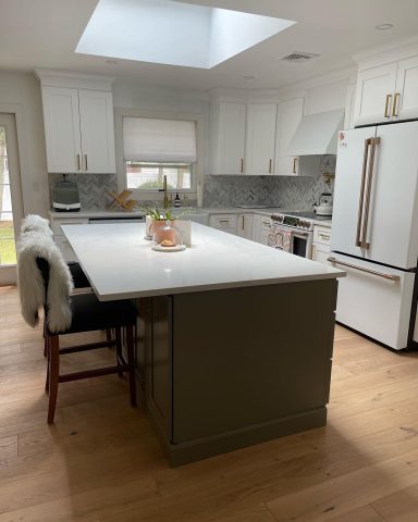 Modern kitchen with white cabinets, a gray island, and a skylight overhead.