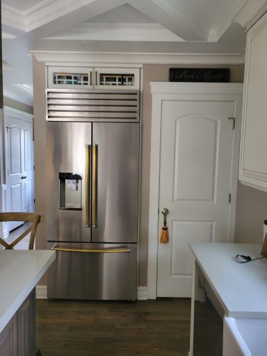 Modern stainless steel refrigerator in a bright kitchen with light-colored cabinetry.