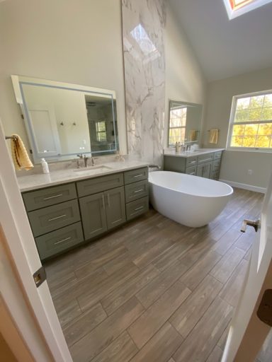 Modern bathroom featuring a freestanding tub, dual sinks, and large mirrors.