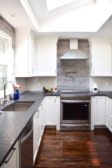 Bright modern kitchen with white cabinets, a gray backsplash, and dark wood floors.