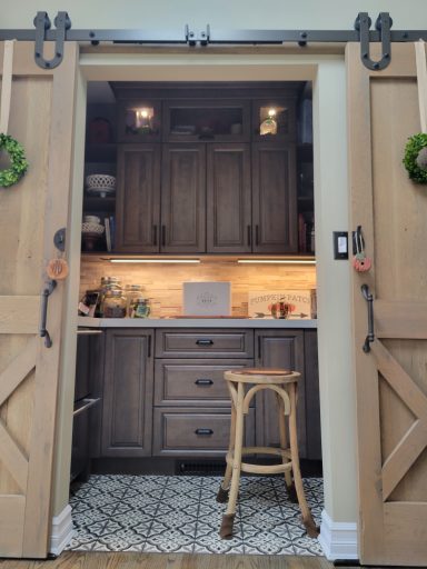 A cozy kitchen nook with wooden sliding doors, a stool, and softly illuminated cabinets.