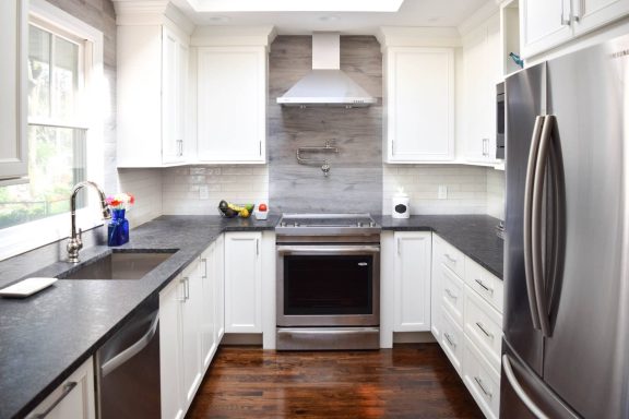 Modern kitchen with white cabinets, stainless steel appliances, and dark countertops.