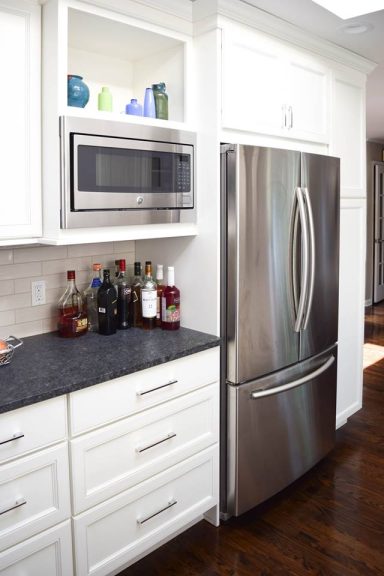 Modern kitchen featuring a stainless steel refrigerator and microwave, with a dark countertop.