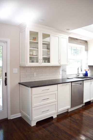 Modern kitchen with white cabinets, dark countertops, and stainless steel appliances.