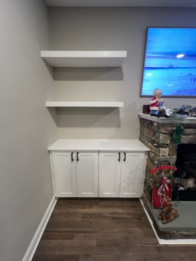 Modern white storage cabinet with two doors and floating shelves above, set against a gray wall.