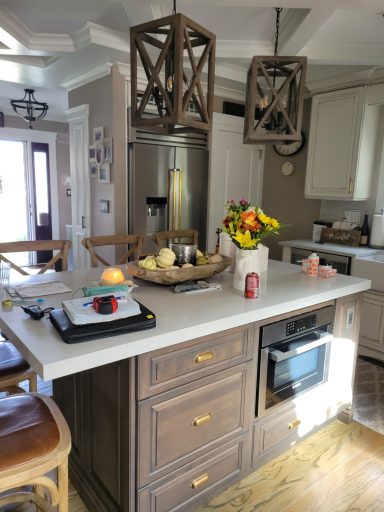 Bright kitchen with a central island, flowers in a vase, and modern light fixtures.