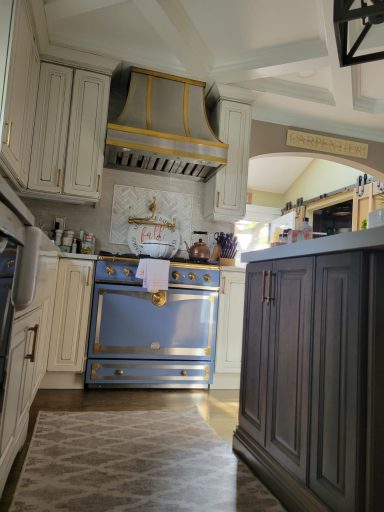 Bright kitchen featuring a blue stove, white cabinets, and elegant wooden accents.