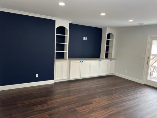 Room featuring dark blue walls, white cabinetry, and hardwood flooring.