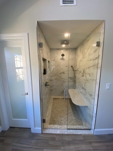 Modern shower with glass enclosure, marble walls, and a built-in bench.