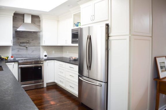 Modern kitchen featuring stainless steel appliances and sleek white cabinetry.