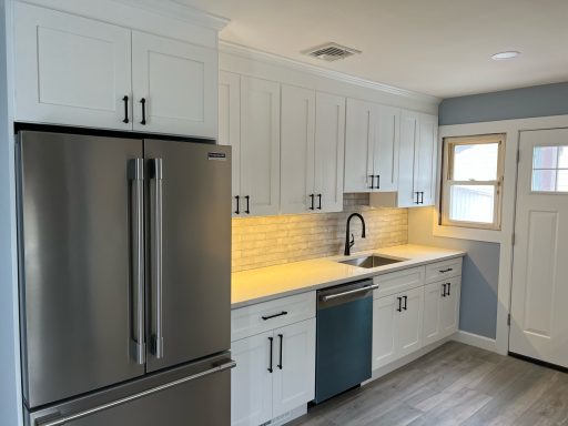 Modern kitchen with white cabinets, stainless steel appliances, and a blue accent on the dishwasher.