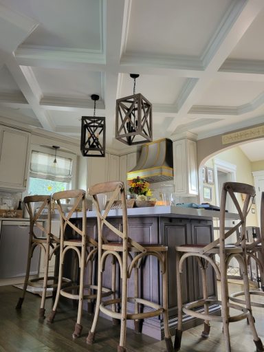 Modern kitchen with coffered ceiling, bar stools, pendant lights, and a central island.