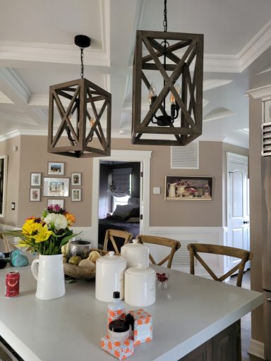 Modern kitchen with wooden pendant lights, flowers, and various kitchenware on a counter.